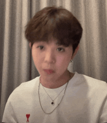 a young man wearing a white t-shirt with a red heart and the letter a on it