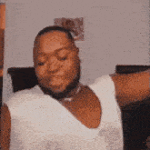 a man with a beard is wearing a white tank top and dancing with his arms outstretched .