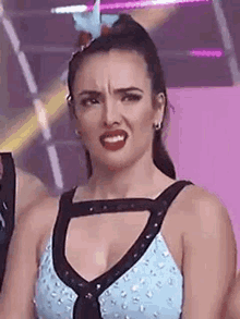 a woman is making a funny face while wearing a blue top .