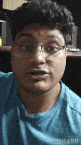 a man wearing glasses and a blue shirt has a gifrun.com watermark at the bottom