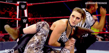 a woman is wrestling another woman in a wrestling ring with a referee in the background .