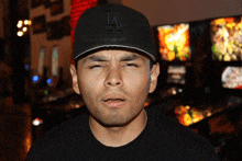 a man wearing a black la hat makes a face