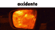 a rear view mirror shows a fire and the word accidente above it