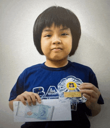 a young boy in a blue shirt is holding a 50 malaysian banknote