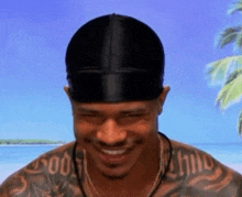 a man with a tattoo on his arm is wearing a black beanie and smiling
