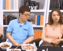 a man and woman are sitting at a table with bowls of food .