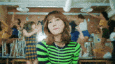 a girl in a green and black striped shirt is standing in front of a group of girls