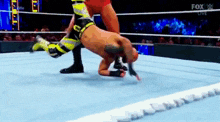 a man is wrestling another man in a wrestling ring on a blue mat .