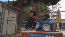 a man playing drums in front of a sign that says " greenway arts "