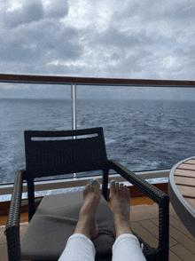 a person with blue toenails is sitting on a chair overlooking the ocean