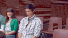 a man in a plaid shirt sits next to a woman in a green jacket