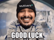 a man wearing a hat that says multivers on it is smiling and says good luck