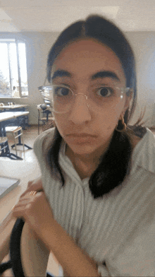a girl wearing glasses and a striped shirt is making a funny face