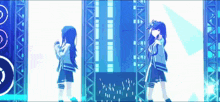 two anime girls are dancing on a stage in front of a large speaker