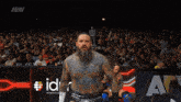 a man with a beard stands in front of a crowd with aew written on the bottom