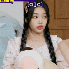 a girl with braids is holding a stuffed animal and has the letter o on her head