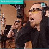 two men wearing sunglasses and headphones are singing into microphones with the hashtag #archivesgroupem6 on the bottom