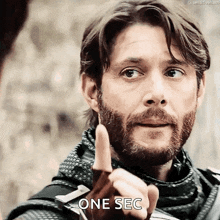 a man with a beard is giving a thumbs up and the word one sec is on the bottom