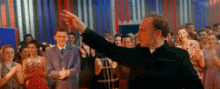 a man is standing in front of a crowd of people and pointing at something