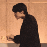 a man in a black suit is standing in front of a wall