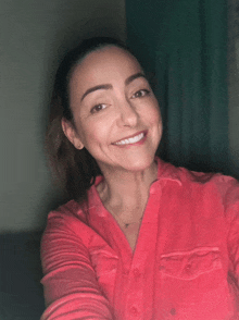 a woman in a red shirt is smiling and taking a selfie