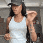 a woman wearing a white tank top and a black hat that says sss on it