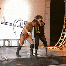 two wrestlers are standing on a stage in front of a wall with the letter w on it