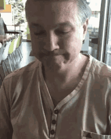 a man with a mustache is sitting at a table with his eyes closed and his mouth open .