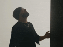 a man with a beard wearing a black shirt and a black beanie