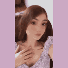 a woman in a purple top is taking a selfie with her hand on her chest