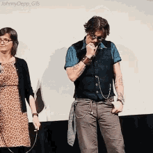 a man with tattoos on his arms is standing next to a woman in a leopard print dress holding a microphone .
