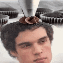 a man 's head is being decorated with chocolate frosting and cupcakes .