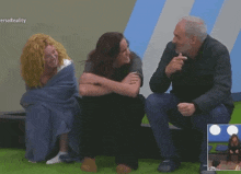 a group of people are sitting on the grass with the word reality on the bottom left