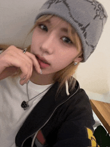 a girl wearing a gray beanie and a black jacket looks at the camera