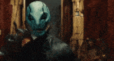 a man with a blue mask on his face is standing in a dark room