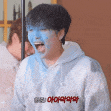 a person with blue paint on their face is wearing a white hoodie with chinese writing on it