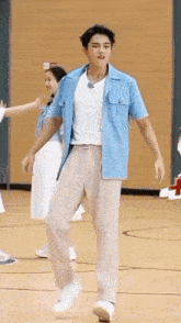 a man in a blue shirt and tan pants is dancing in a gym .