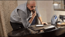 a man sitting at a desk with a telephone and a notepad