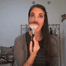 a woman is applying makeup in front of a sign that says popcorn now showing