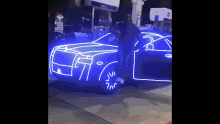 a man is standing in front of a blue car that is lit up