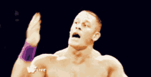 a shirtless wrestler is pointing at the camera with a w live logo behind him