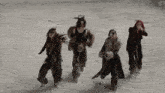 a group of women are dancing in the dirt with a s on the bottom right