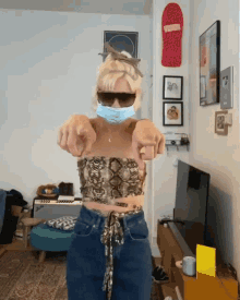 a woman wearing a face mask and sunglasses points her fingers at the camera