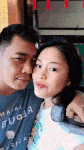 a man and a woman are posing for a picture and the woman is wearing a shirt that says ' a ' on it