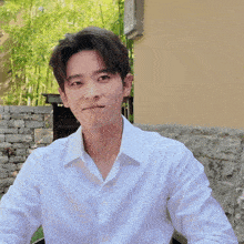 a young man wearing a white shirt is sitting in front of a building