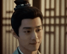 a close up of a man 's face with a bun in his hair