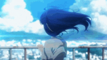 a girl with blue hair is standing on a balcony looking at the ocean .