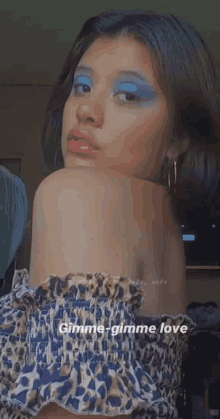 a woman wearing blue eyeshadow and red lipstick is taking a selfie .