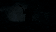 a statue of a man in armor holding a spear on a black background
