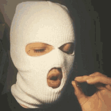a person wearing a white ski mask with a hole in the face